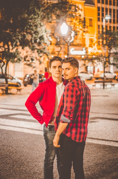 Two young men stand very close to the square in the city at night
